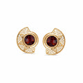 A pair of gold filigree stud earrings featuring round deep red garnet centers and small clear accent stones, shown on a plain white background.