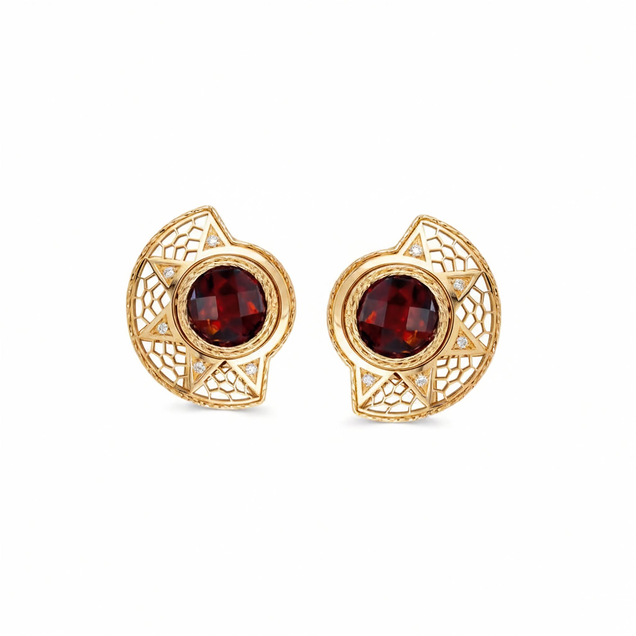 A pair of gold filigree stud earrings featuring round deep red garnet centers and small clear accent stones, shown on a plain white background.
