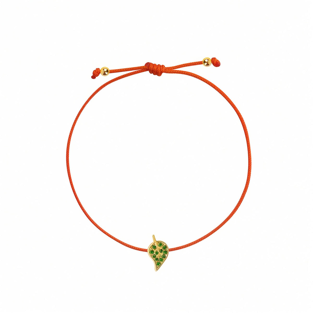 18k Gold Leaf String Bracelet with Natural Tsavorites. An orange cord bracelet featuring a small yellow gold leaf charm embellished with green stones, displayed on a clean white background.
