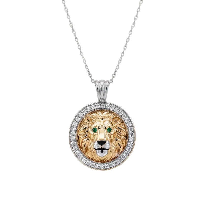 A white gold chain necklace with a round pendant featuring a detailed lion head in gold and silver, with green eyes and a halo of small white diamonds.