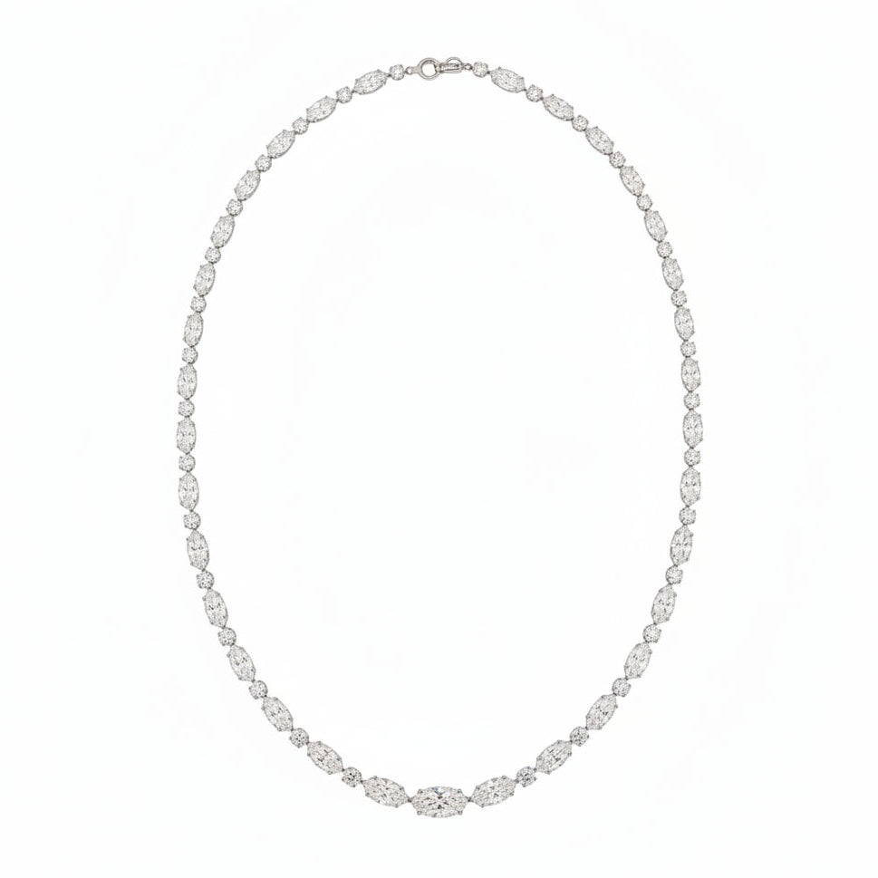 A white gold tennis necklace featuring a continuous link pattern of oval and round cut diamonds, displayed on a solid white background.