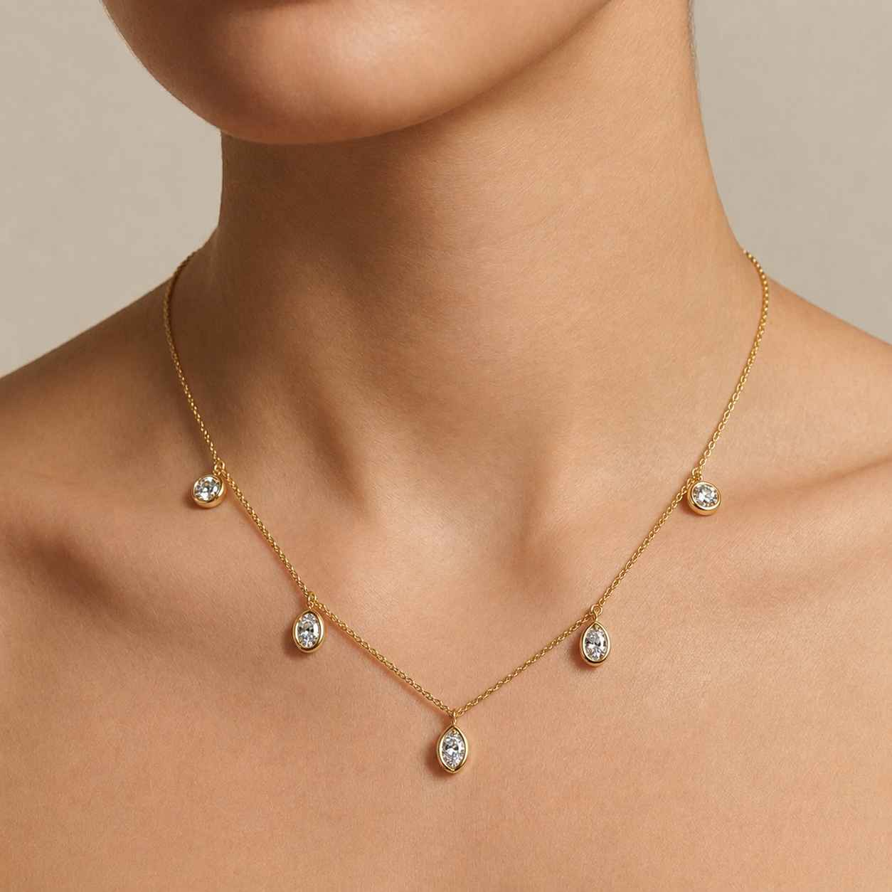 Yellow Gold necklace with small drop bezel set diamonds on a model.