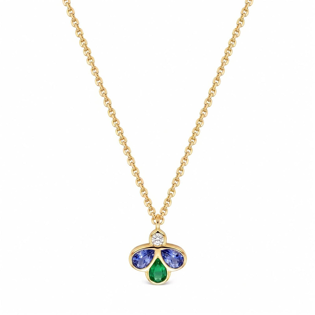 A gold chain necklace with a small clover-shaped pendant featuring a central round diamond, a two blue gemstones, and a bottom green teardrop gemstone, shown on a plain white background.