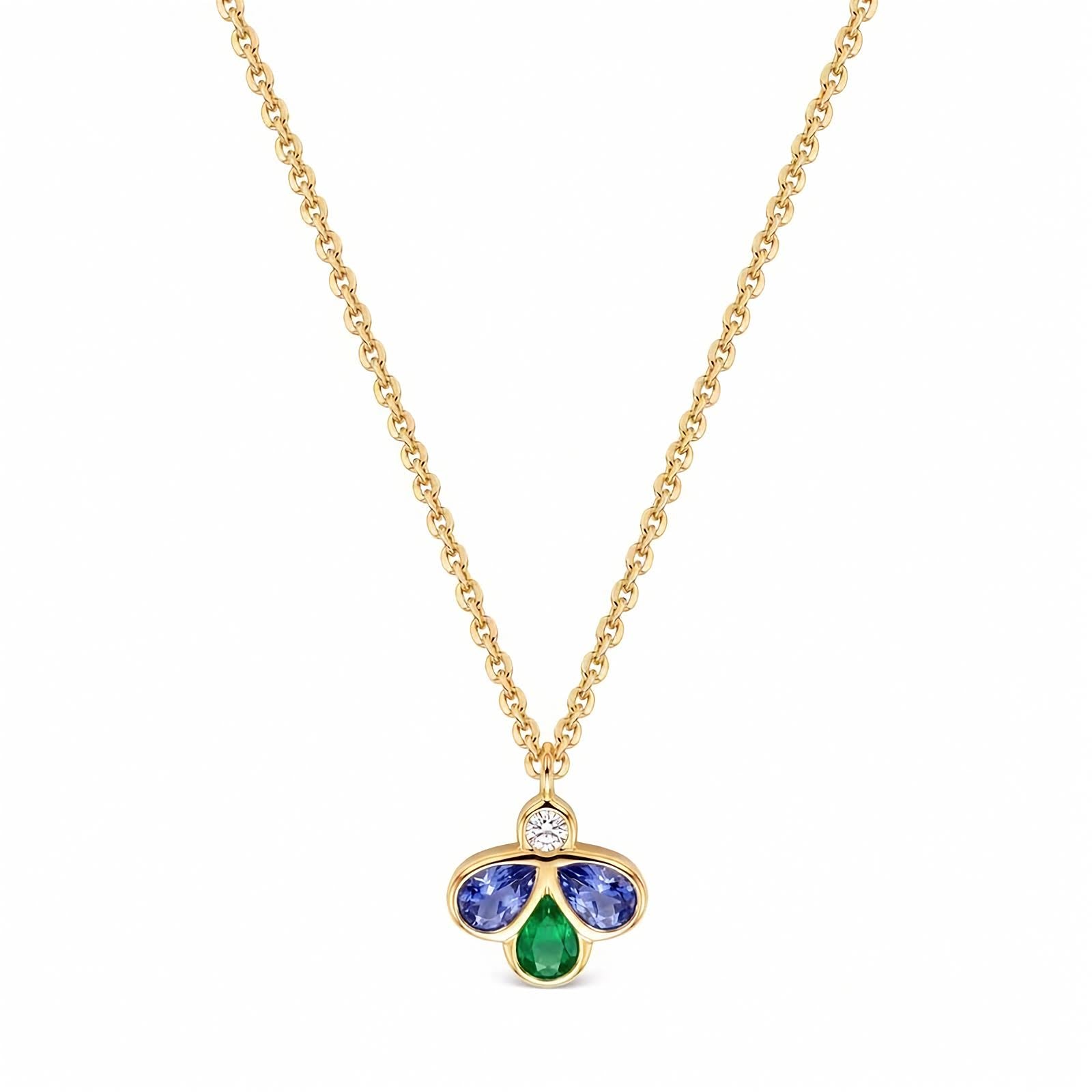A gold chain necklace with a small clover-shaped pendant featuring a central round diamond, a two blue gemstones, and a bottom green teardrop gemstone, shown on a plain white background.