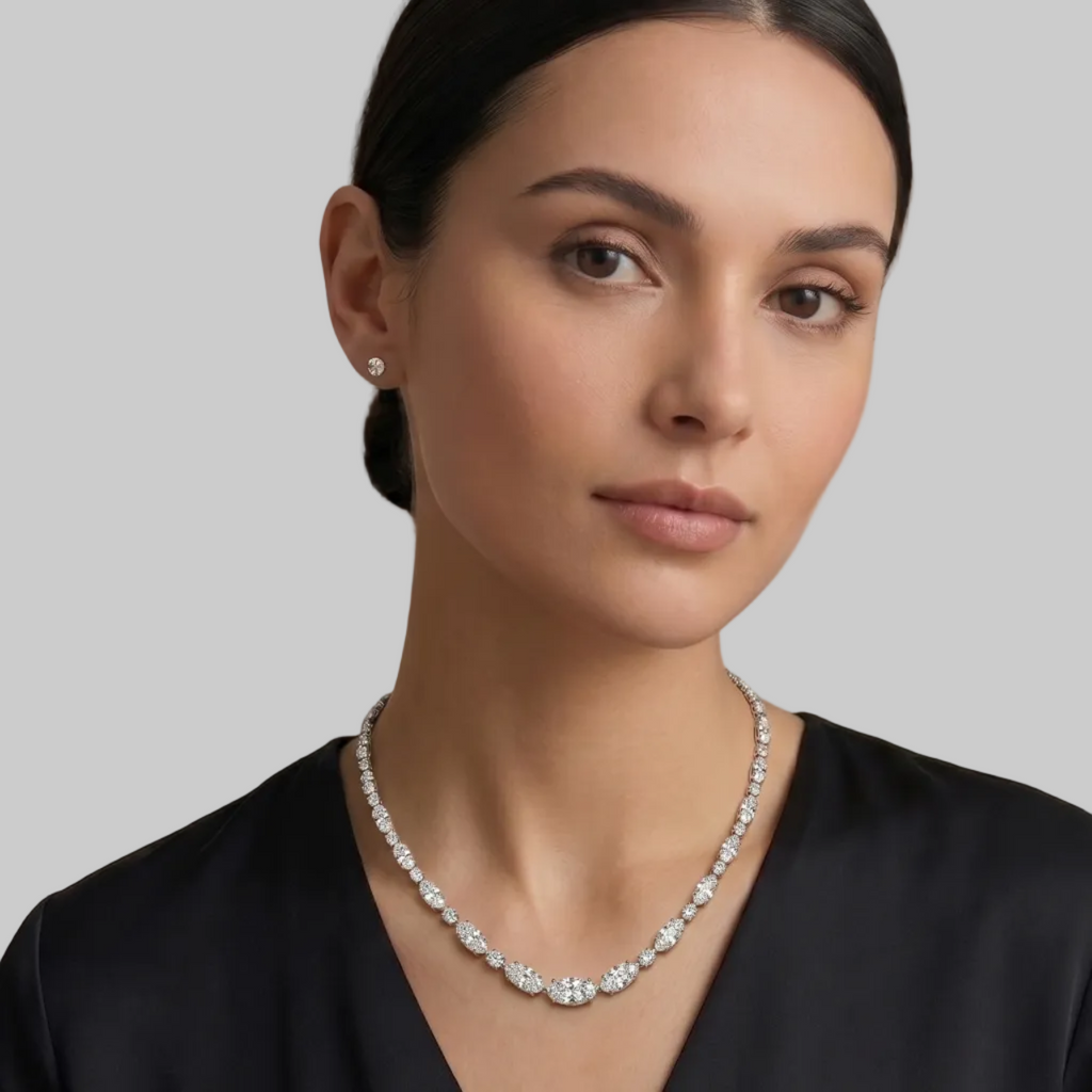 A white gold tennis necklace featuring a continuous link pattern of oval and round cut diamonds, displayed on a model.
