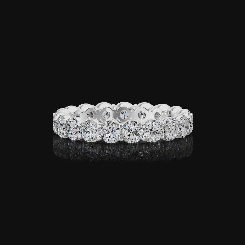 Spinning diamond eternity ring in a silver-colored metal setting, featuring a continuous row of round brilliant-cut diamonds on a plain black background.