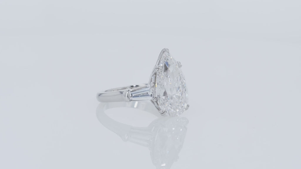 Video of a diamond ring with pear-shaped center stone and tapered baguettes side diamonds on a gray background.