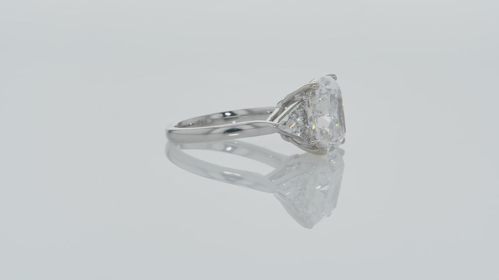 Video of Cushion Cut Diamond And Trillion diamonds on the side - Three Stone Ring in White Gold on a gray background.