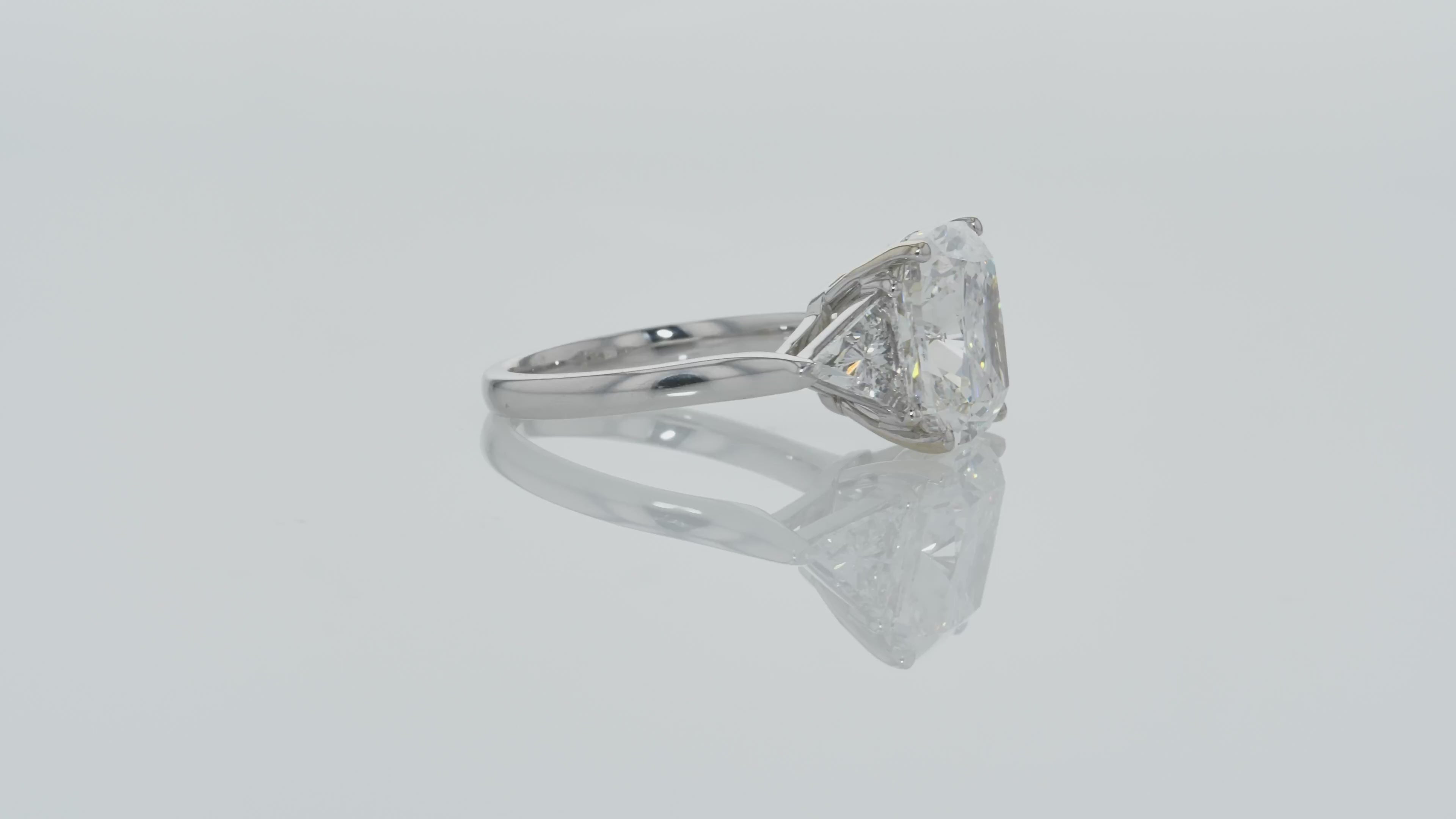Video of Cushion Cut Diamond And Trillion diamonds on the side - Three Stone Ring in White Gold on a gray background.