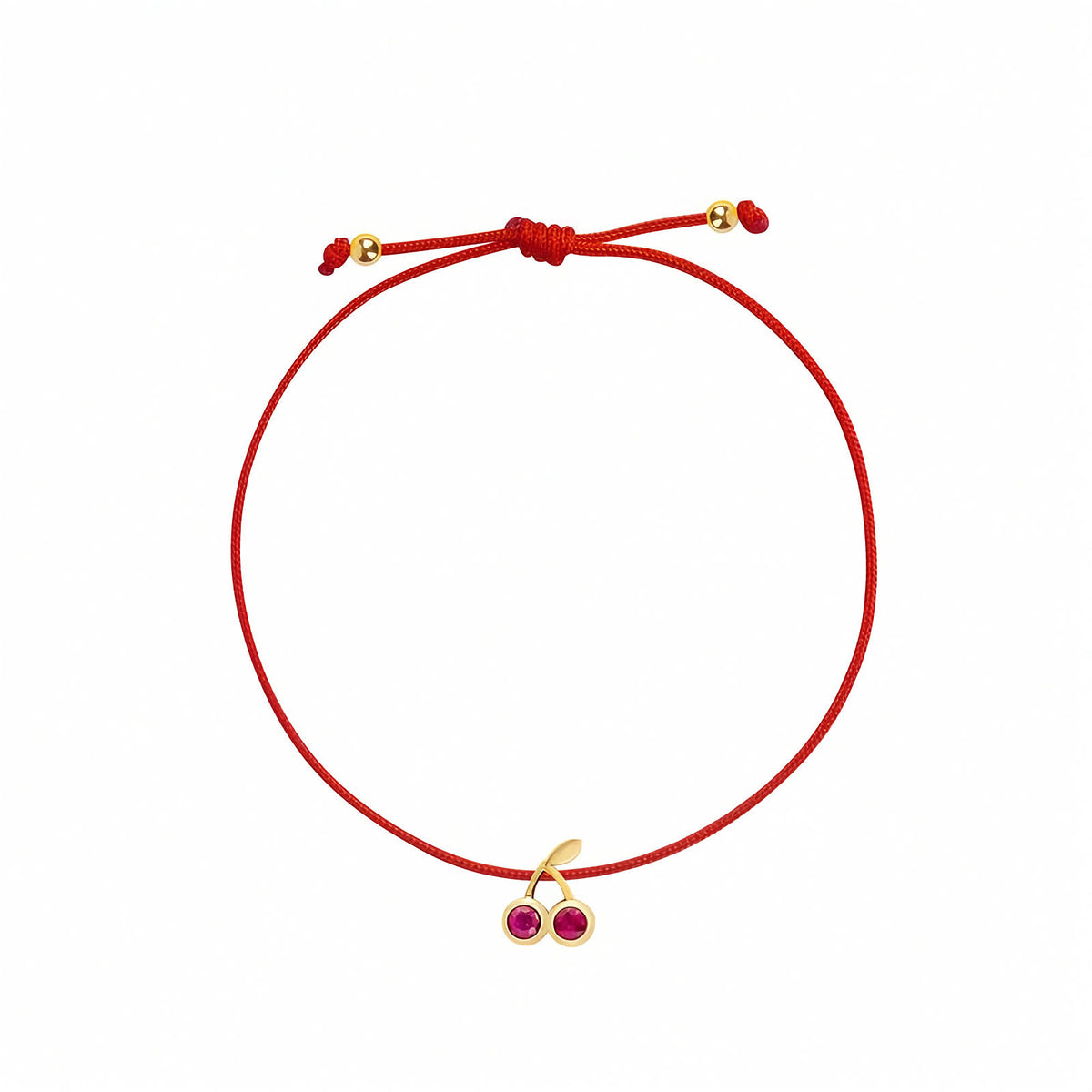 Rosmundo collaboration 18k yellow gold cherry string bracelet with natural rubies on adjustable red macramé cord. A red adjustable cord bracelet featuring a small gold-tone cherry charm with two pinkish-red gemstone centers, displayed on a clean white background.