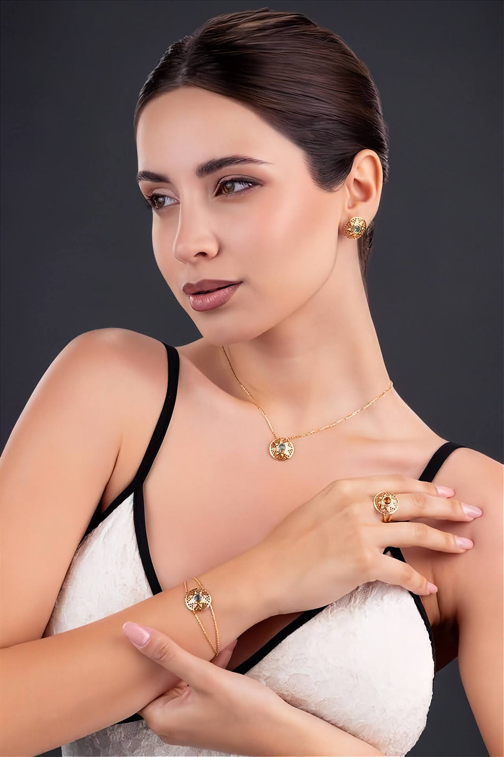 A gold chain necklace with circular pendant  and yellow gemstone accent, shown on a model.
