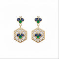 A pair of gold drop earrings featuring a hexagonal openwork design with white inlay, accented by blue and green enamel-like sections and a small round diamond at the top.
