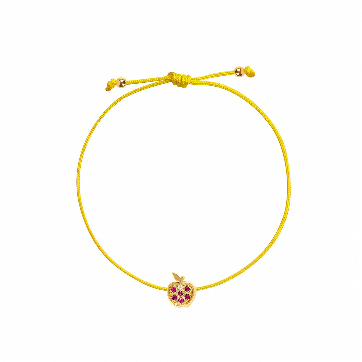 Rosmundo collaboration 18k yellow gold apple string bracelet with natural rubies and diamond on adjustable macrame cord. A green adjustable cord bracelet featuring a small yellow gold apple charm embellished with purple gemstones, set against a plain white background.