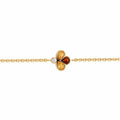 A delicate yellow gold chain bracelet featuring a central clover-like charm with two yellow gemstones, one amber-orange gemstone, and a small clear accent diamond, shown on a plain white background.