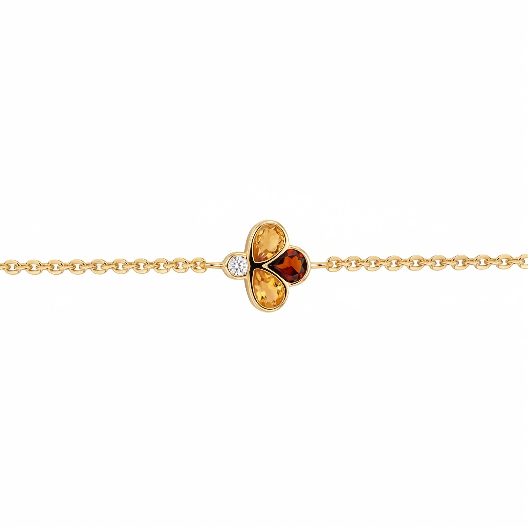 A delicate yellow gold chain bracelet featuring a central clover-like charm with two yellow gemstones, one amber-orange gemstone, and a small clear accent diamond, shown on a plain white background.